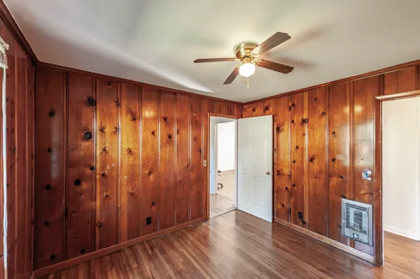 a view of an empty room with a window and wooden floor