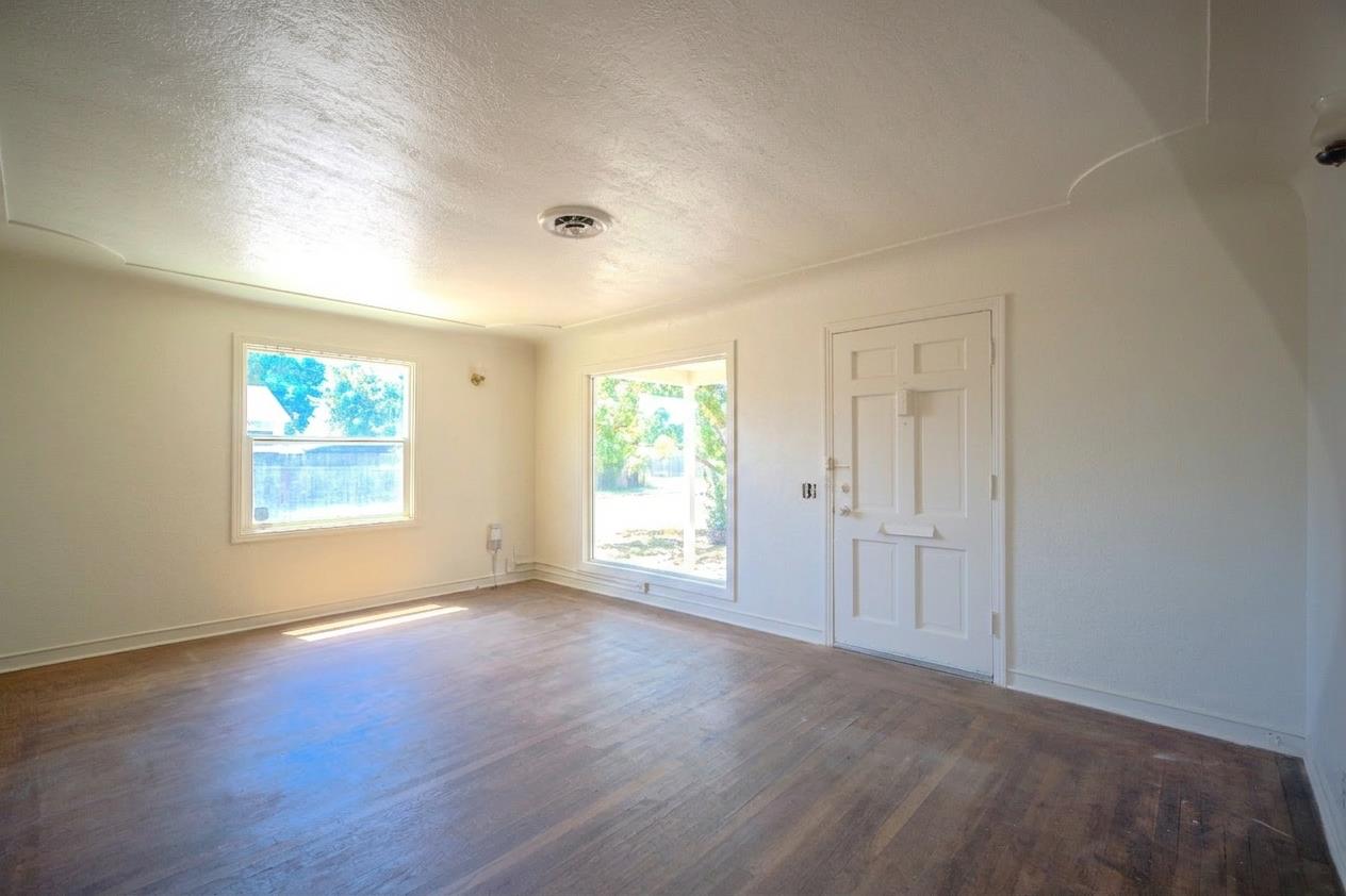 214 Ferguson Avenue Modesto, CA 95354 - Photo 5 of 14 an empty room with wooden floor and windows