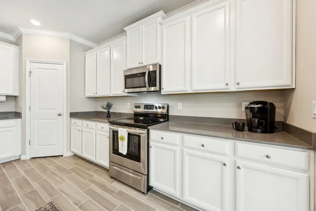 a kitchen with granite countertop white cabinets and stainless steel appliances