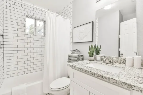 a bathroom with a granite countertop sink toilet and shower