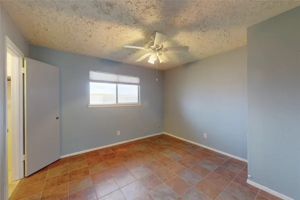 an empty room with a chandelier fan and windows