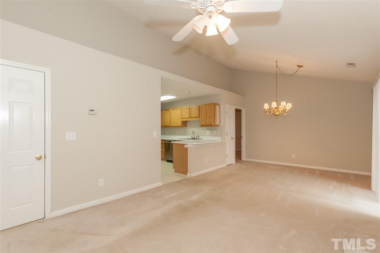 9000 Shallcross Way Raleigh, NC 27617 - Photo 16 of 25 an empty room with kitchen view and a chandelier