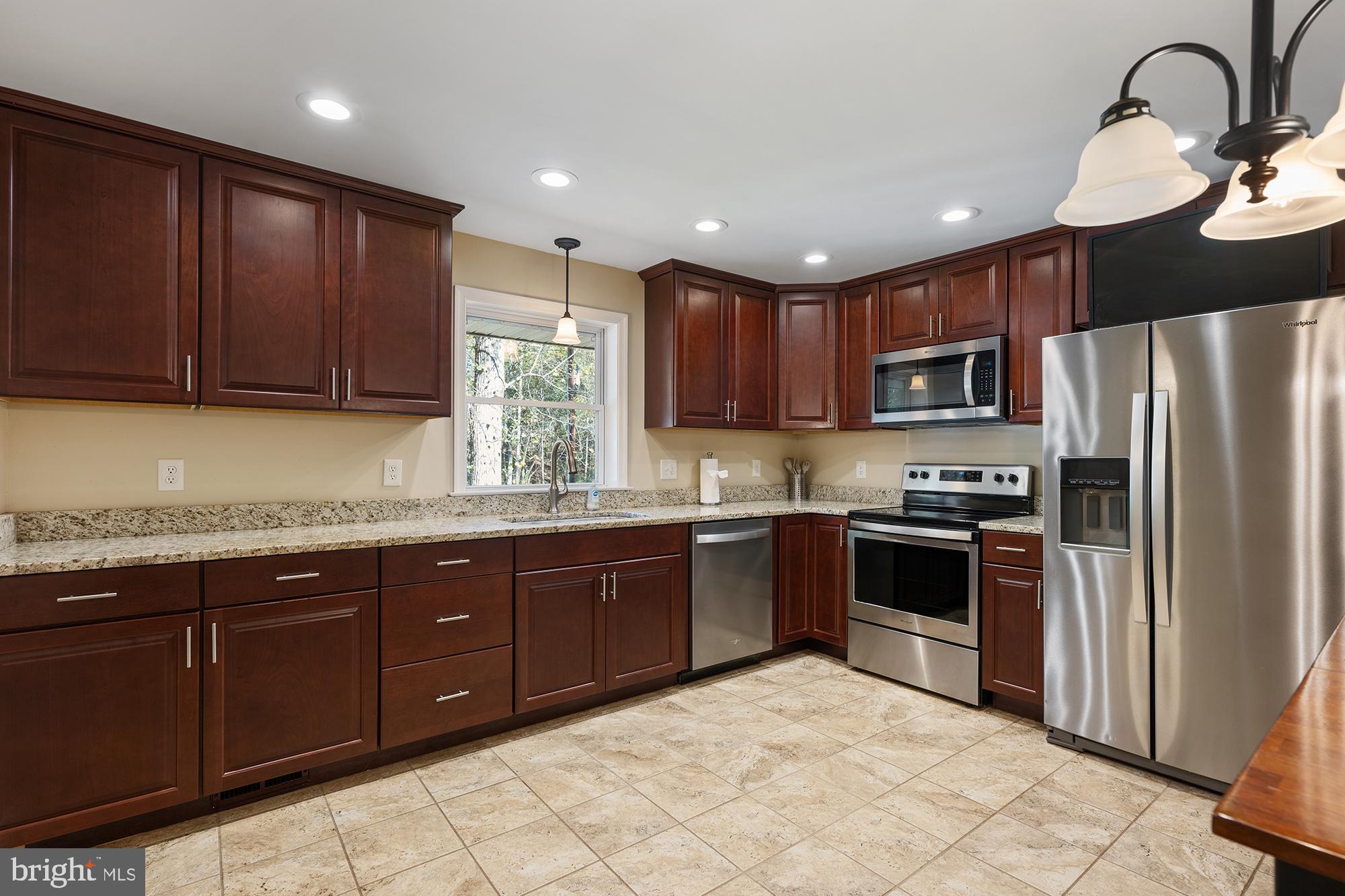 4010 Greenmount Church Road Hampstead, MD 21074 - Photo 11 of 32 a kitchen with stainless steel appliances granite countertop wooden cabinets a stove a sink and a microwave