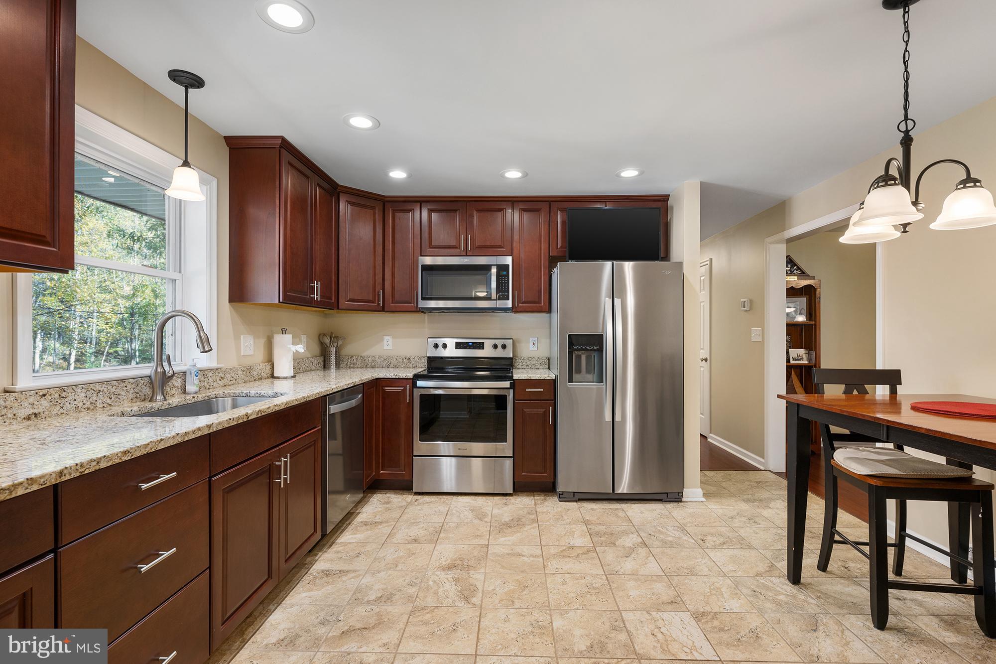 4010 Greenmount Church Road Hampstead, MD 21074 - Photo 12 of 32 a kitchen with stainless steel appliances granite countertop a refrigerator a sink a stove a microwave and a dining table with wooden floor