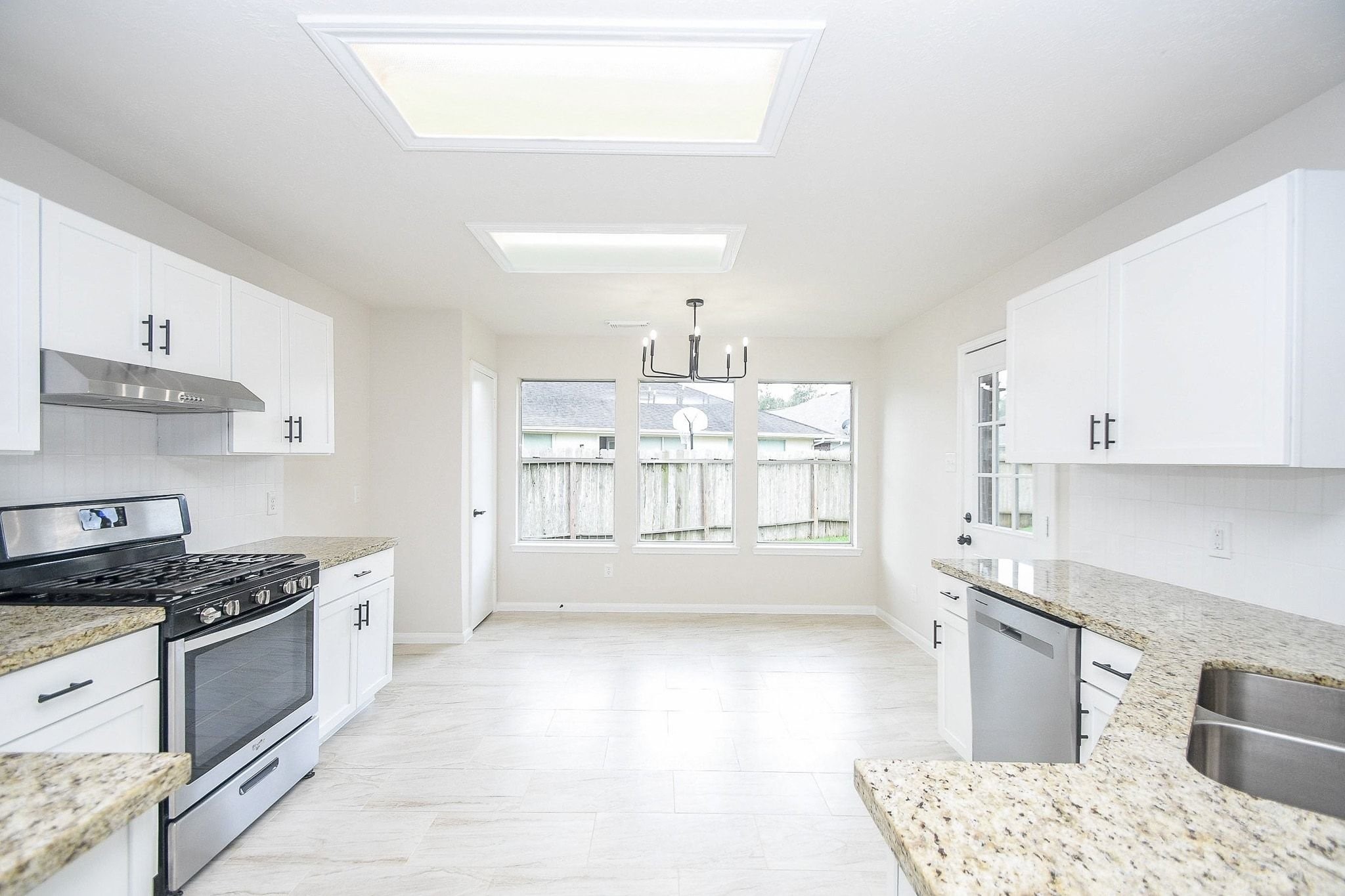 1422 Township Court Rosenberg, TX 77471 - Photo 13 of 32 a kitchen with granite countertop a stove a sink and white cabinets