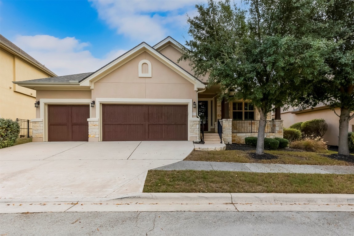 View of front facade featuring stucco siding, an attached garage, stone siding, concrete driveway, and covered porch
