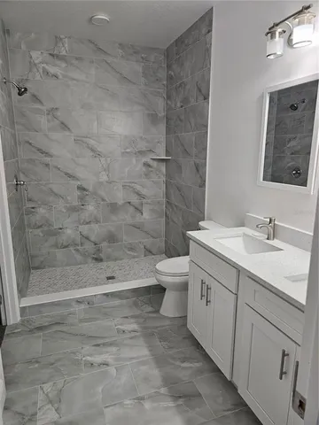 a bathroom with a granite countertop sink toilet and shower