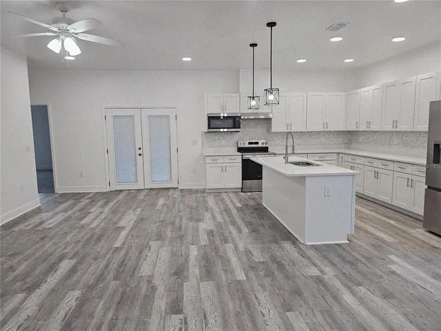 a kitchen with a hard wood floor window and stainless steel appliances