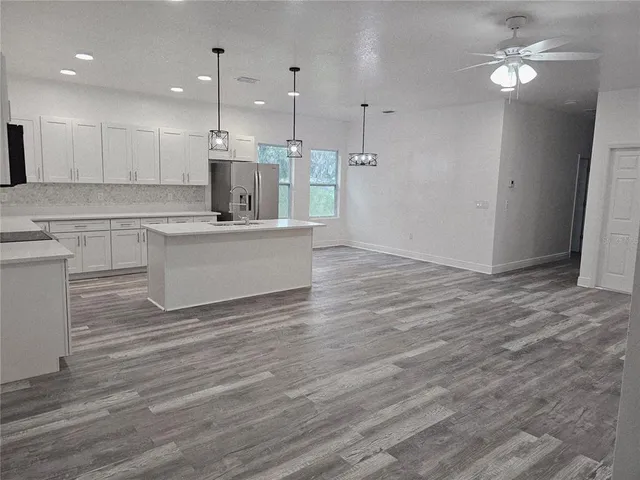 a view of kitchen with granite countertop refrigerator oven and white cabinets