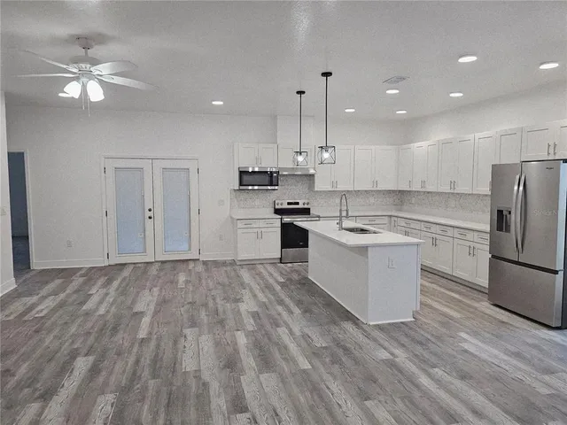 a large kitchen with cabinets wooden floor and stainless steel appliances