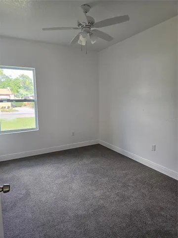 an empty room with a window and a fan