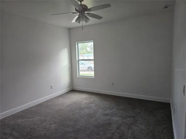 an empty room with a window and a fan