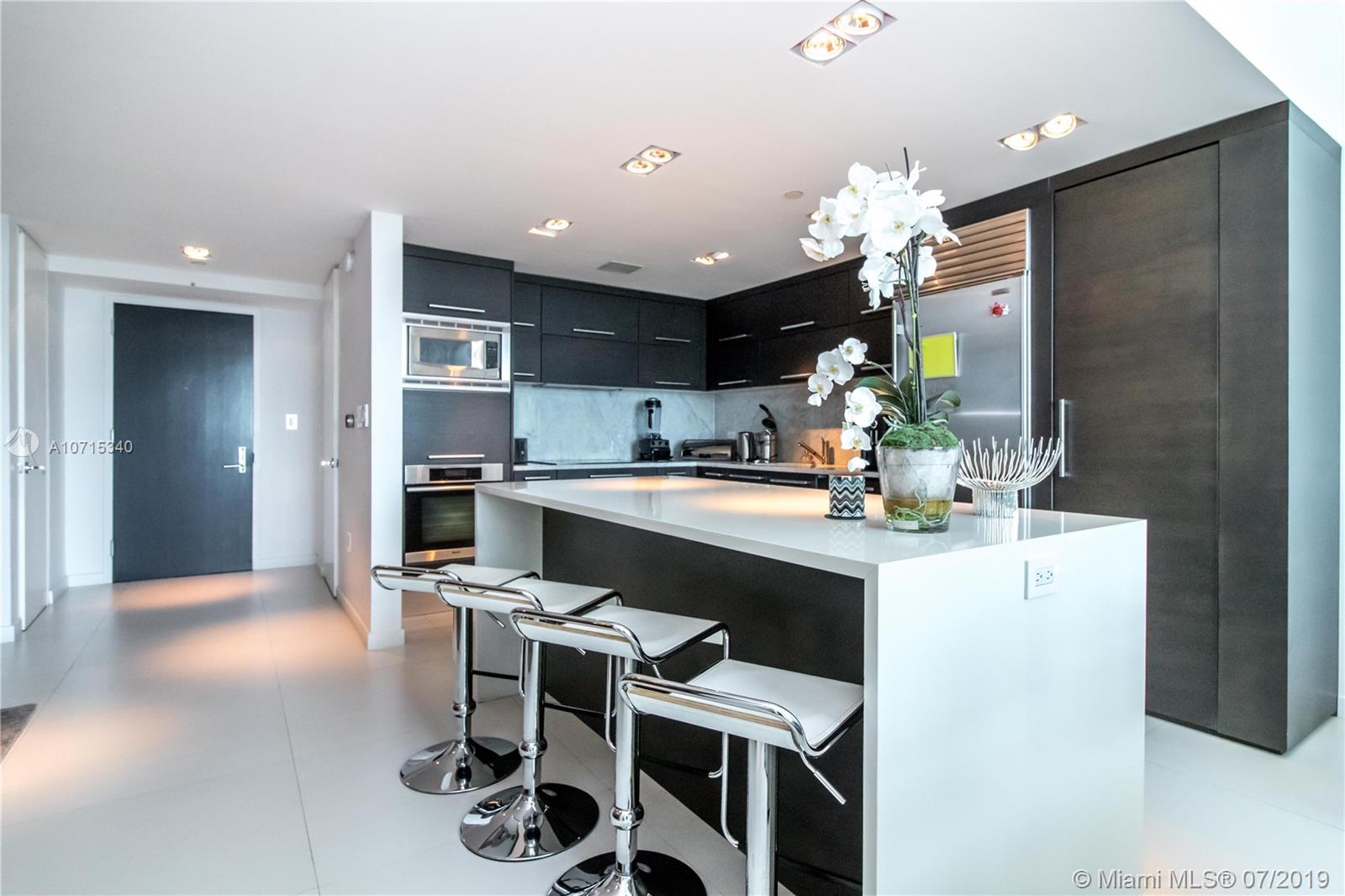 900 Biscayne Boulevard, Unit 705 Miami, FL 33132 - Photo 5 of 43 a kitchen with kitchen island granite countertop a sink cabinets and refrigerator