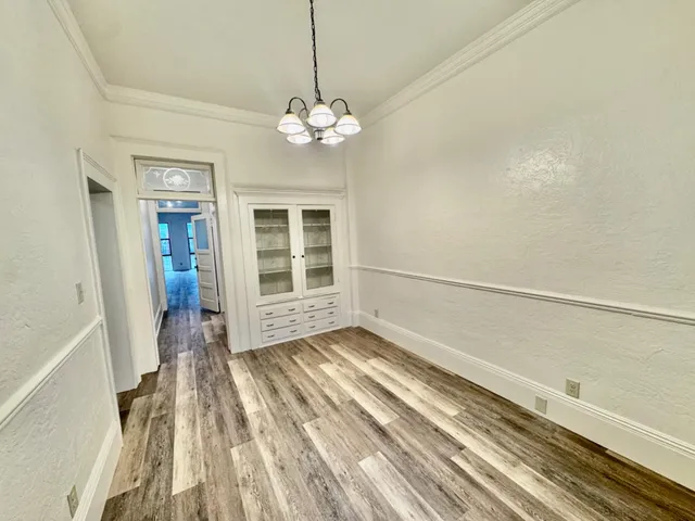 a view of empty room with cabinet and wooden floor