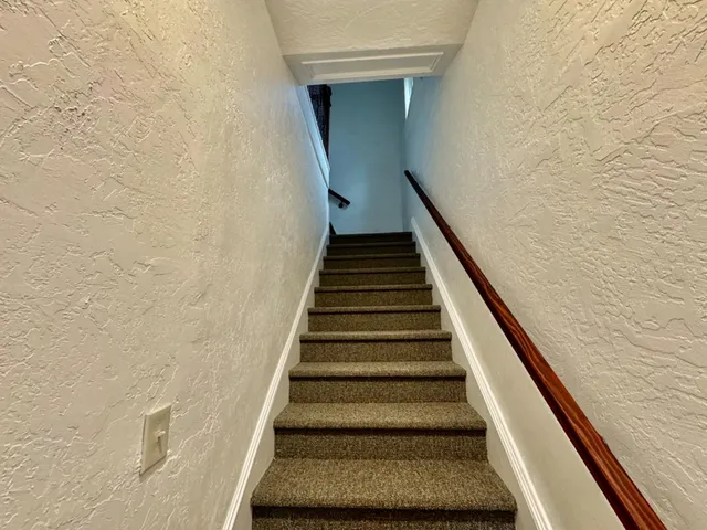 a view of a hallway with wooden floor and a bathroom