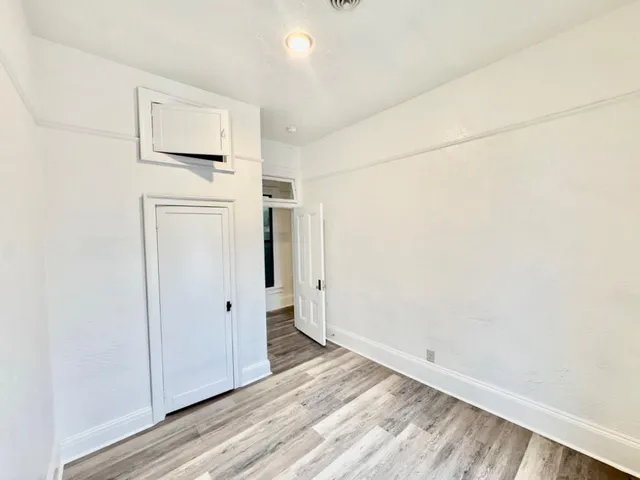 a view of a hallway with wooden floor and a bathroom