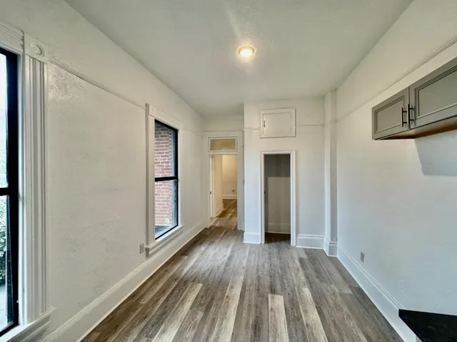 a view of an empty room with wooden floor and painting on the wall