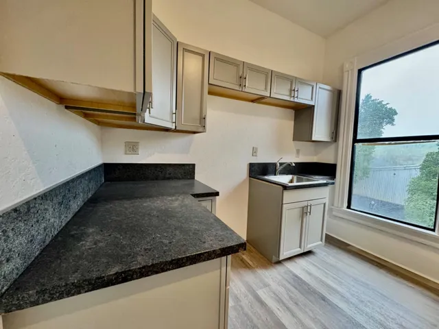 a backyard of a house with wooden fence and large trees