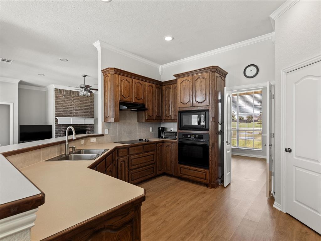10066 Irish Ridge Forney, TX 75126 - Photo 20 of 39 Kitchen with black appliances, under cabinet range hood, a ceiling fan, ornamental molding, and light countertops