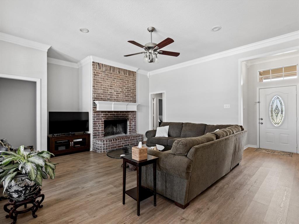 10066 Irish Ridge Forney, TX 75126 - Photo 2 of 39 Living area with a ceiling fan, ornamental molding, wood finished floors, and a brick fireplace