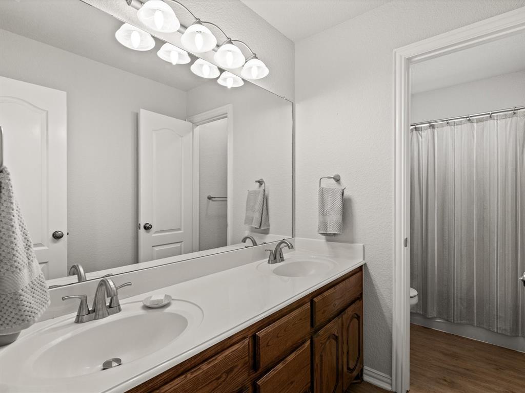 10066 Irish Ridge Forney, TX 75126 - Photo 25 of 39 Bathroom with double vanity, wood finished floors, and a shower with shower curtain