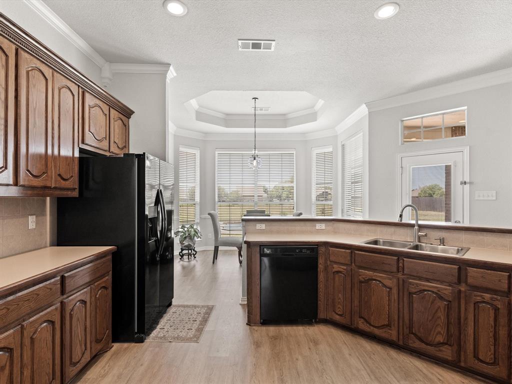 10066 Irish Ridge Forney, TX 75126 - Photo 27 of 39 Kitchen with black appliances, ornamental molding, light wood-style floors, hanging light fixtures, and light countertops