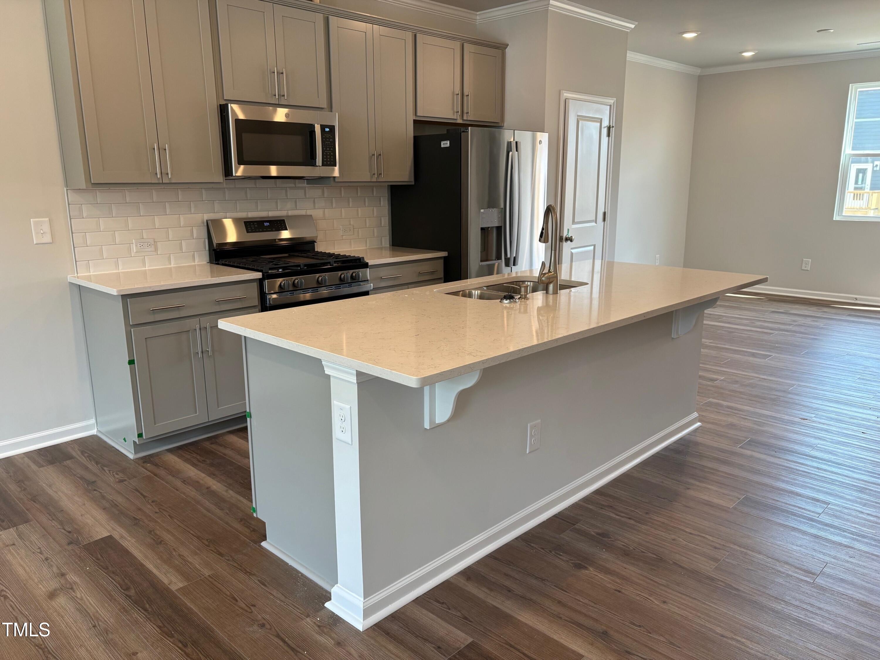 331 Deercroft Drive Apex, NC 27539 - Photo 5 of 21 a kitchen with stainless steel appliances a sink a stove a microwave and wooden floor
