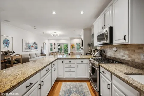a large kitchen with granite countertop a sink a stove a oven a counter space and cabinets