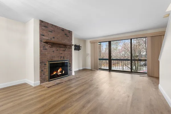 a view of an empty room with wooden floor and a fireplace