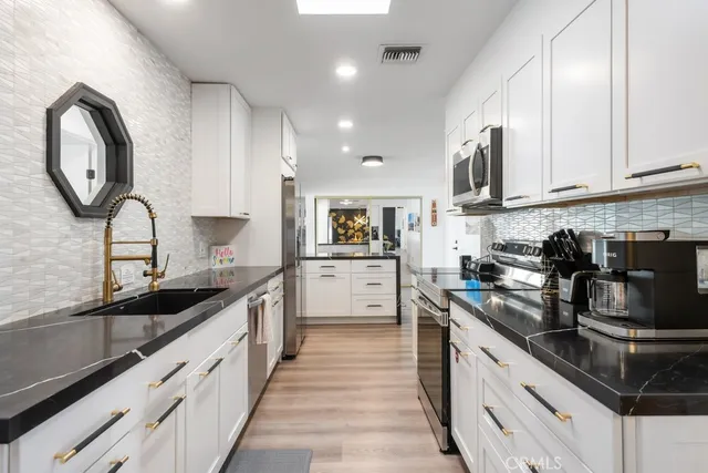 a kitchen with granite countertop white cabinets and stainless steel appliances