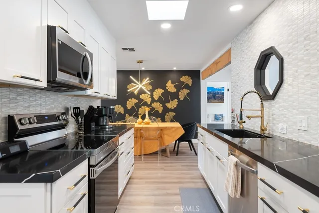 a kitchen with stainless steel appliances a sink a stove and cabinets