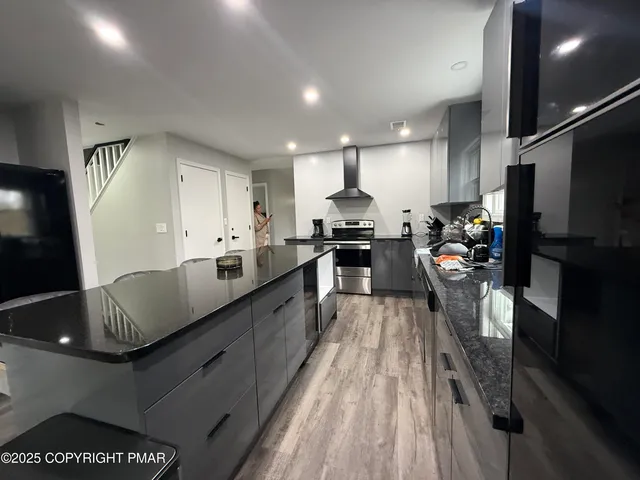 a large kitchen with stainless steel appliances kitchen island granite countertop a lot of counter space and a sink