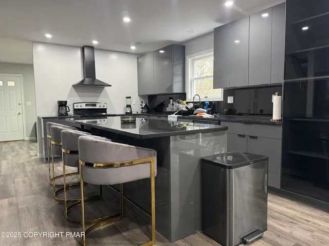 a kitchen with stainless steel appliances granite countertop a sink a stove a refrigerator and chairs