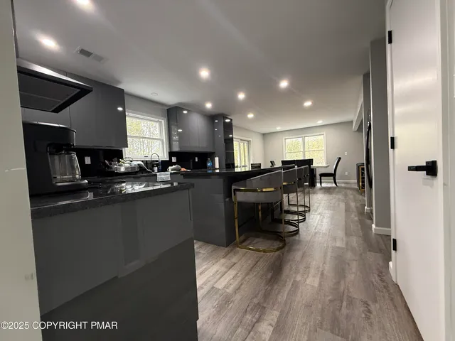 a kitchen with stainless steel appliances kitchen island granite countertop a refrigerator oven a sink a dining table and chairs with wooden floor