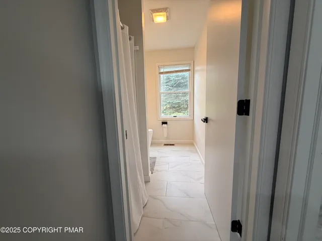 a view of a hallway with wooden floor and a bathroom