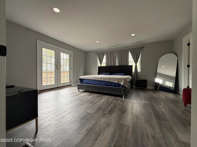 a spacious bedroom with a bed and wooden floor