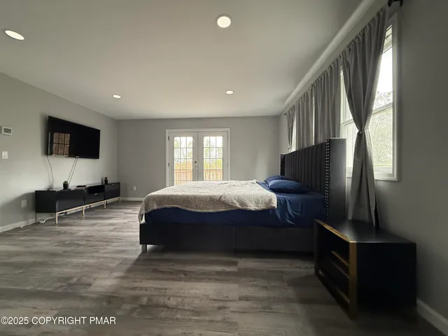 a spacious bedroom with a bed and a flat screen tv