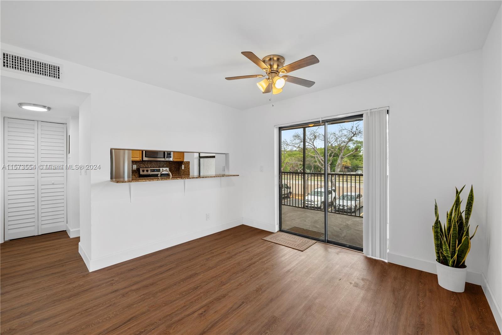 a view of empty room with wooden floor and fan