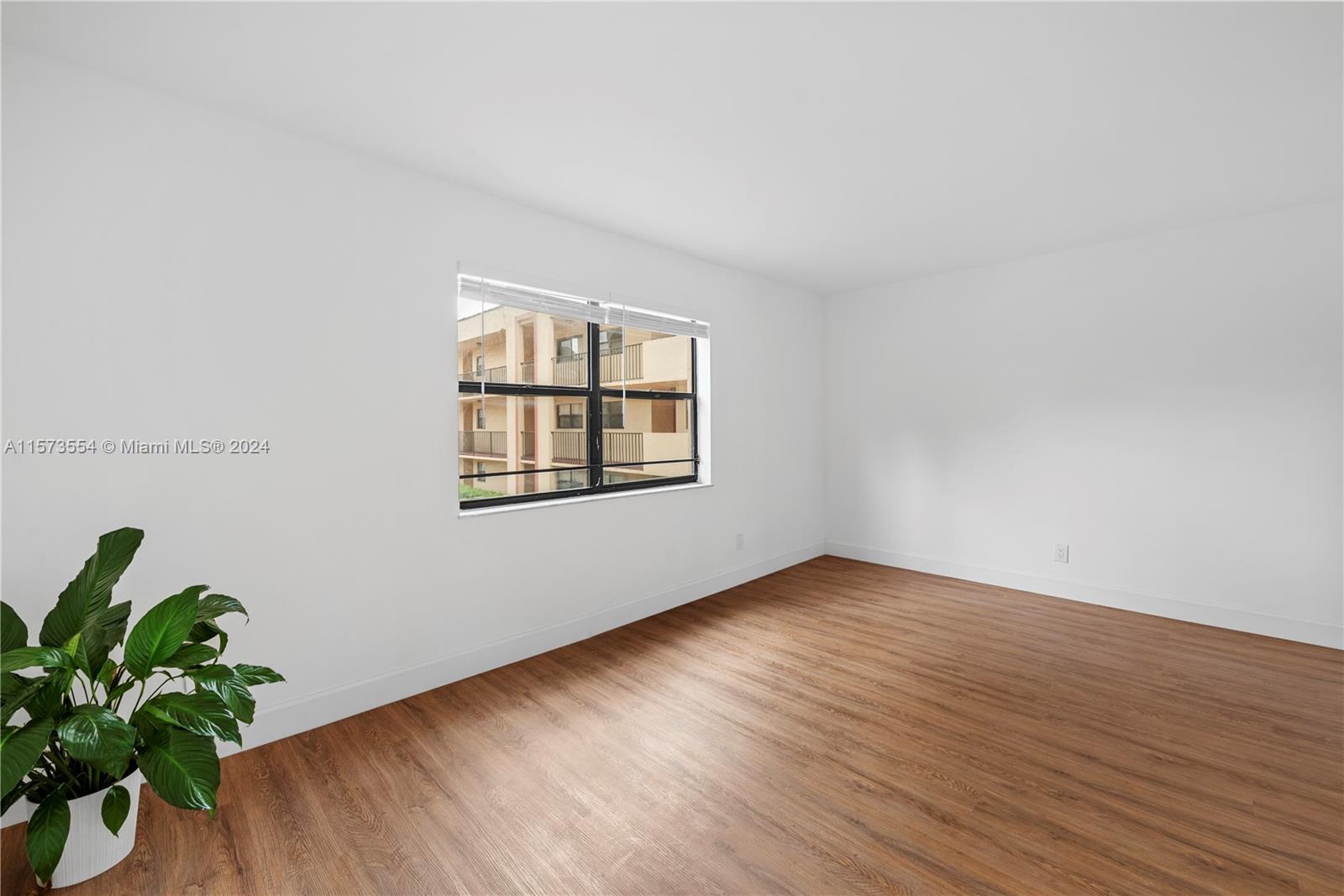 3252 Foxcroft Road, Unit 216 Miramar, FL 33025 - Photo 12 of 16 an empty room with wooden floor and plant