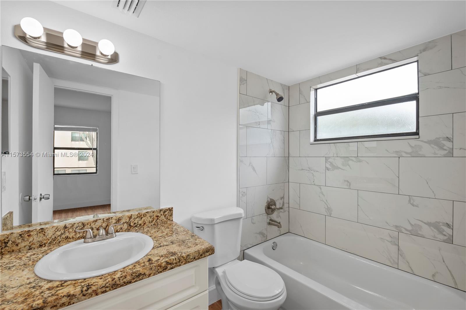3252 Foxcroft Road, Unit 216 Miramar, FL 33025 - Photo 13 of 16 a bathroom with a granite countertop sink toilet a mirror and bathtub