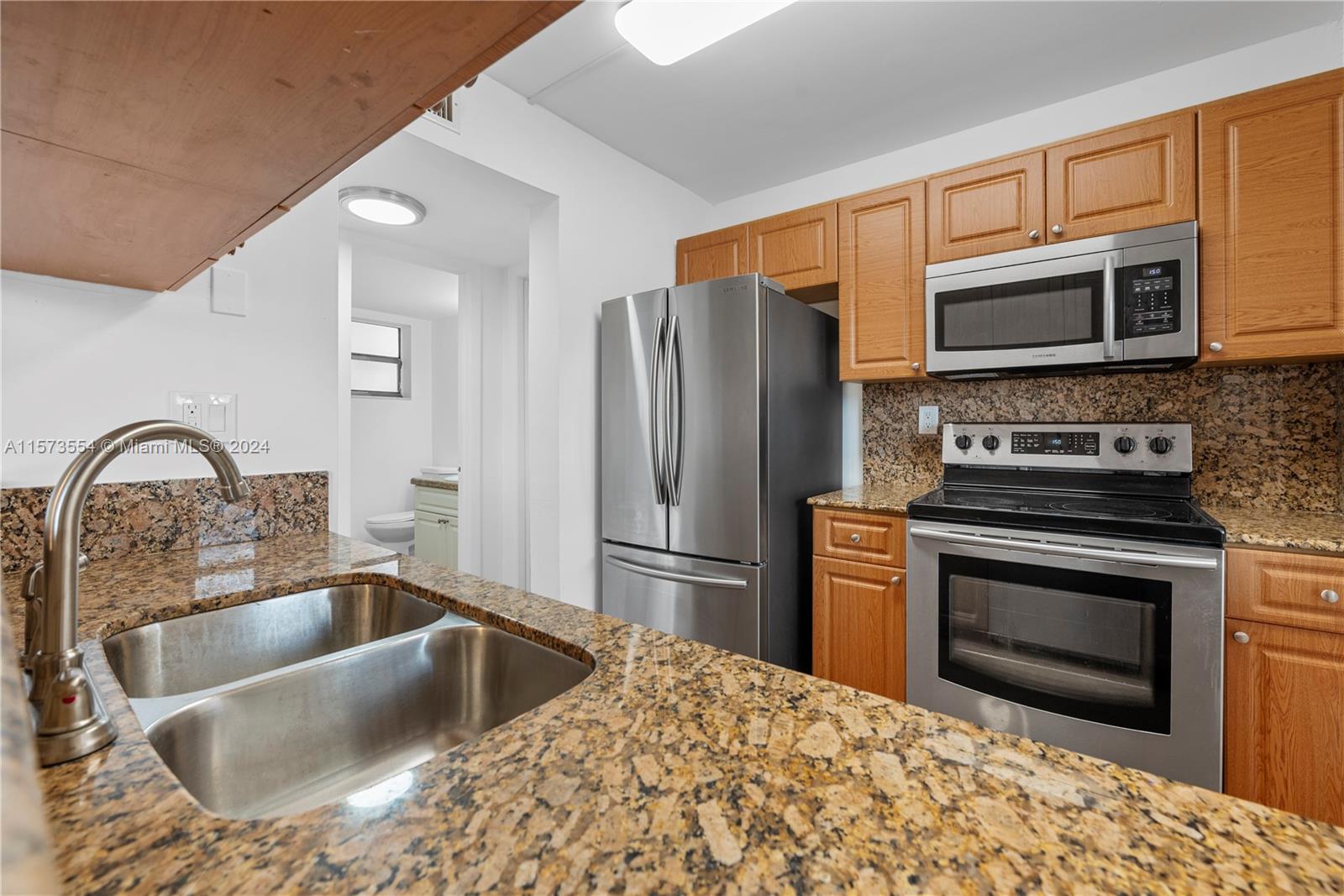 3252 Foxcroft Road, Unit 216 Miramar, FL 33025 - Photo 5 of 16 a kitchen with stainless steel appliances granite countertop a sink stove and refrigerator