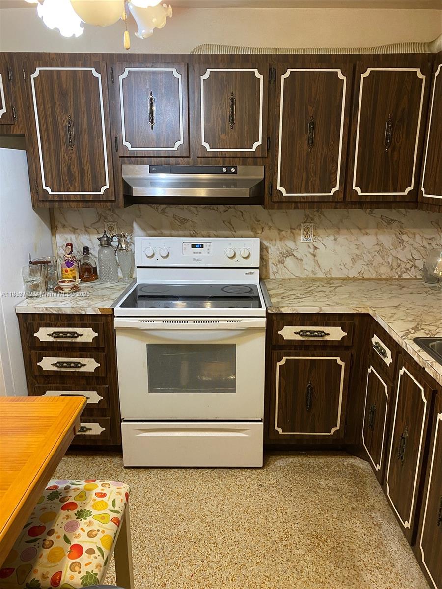 8120 Southwest 10th Terrace Miami, FL 33144 - Photo 7 of 12 a kitchen with granite countertop wood cabinets stainless steel appliances and a stove