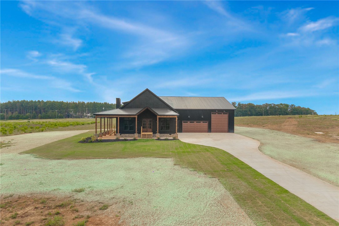 384 Jim Smith Road Pendleton, SC 29670 - Photo 40 of 48 A striking modern farmhouse exterior showcasing a bold dark facade and a spacious wrap-around porch.