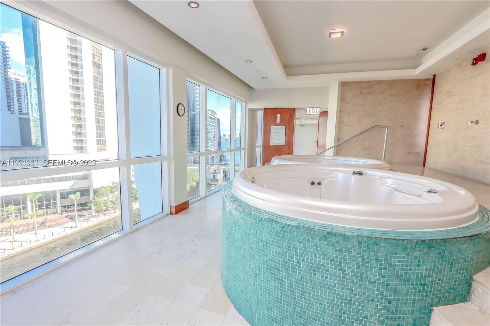 31 Southeast 5th Street, Unit 2907 Miami, FL 33131 - Photo 30 of 38 a white bath tub sitting in a bathroom next to a window