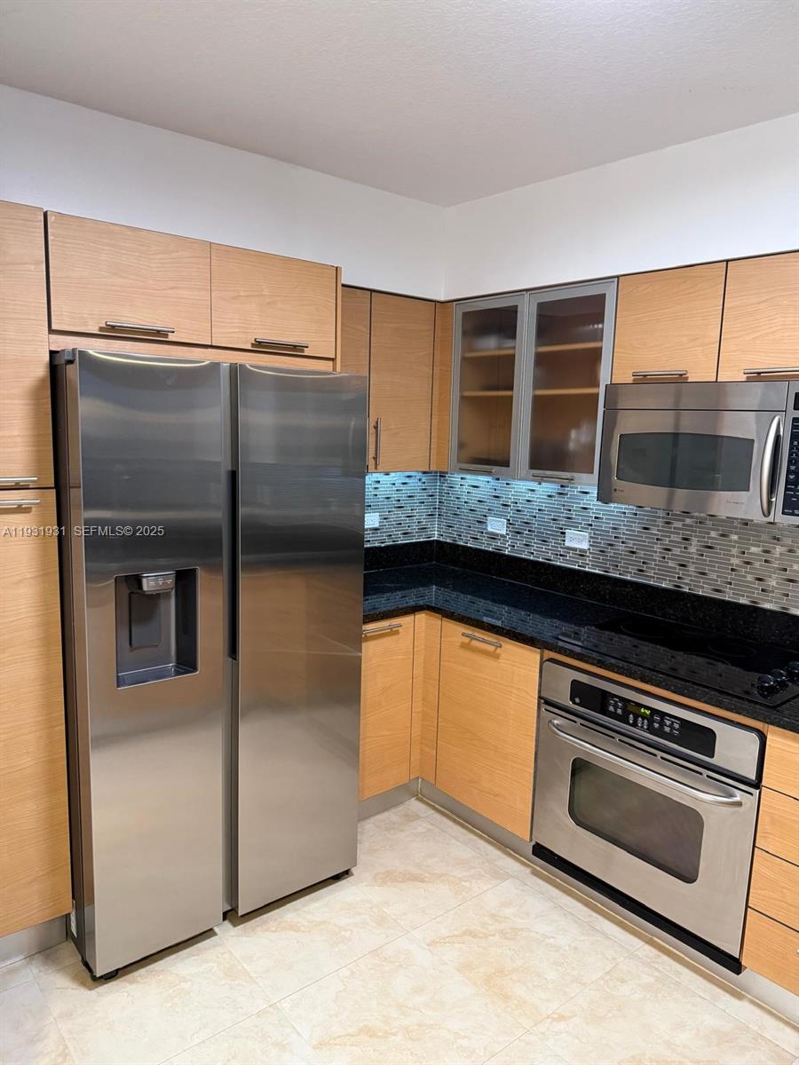 31 Southeast 5th Street, Unit 2907 Miami, FL 33131 - Photo 5 of 38 a kitchen with granite countertop a refrigerator and a stove