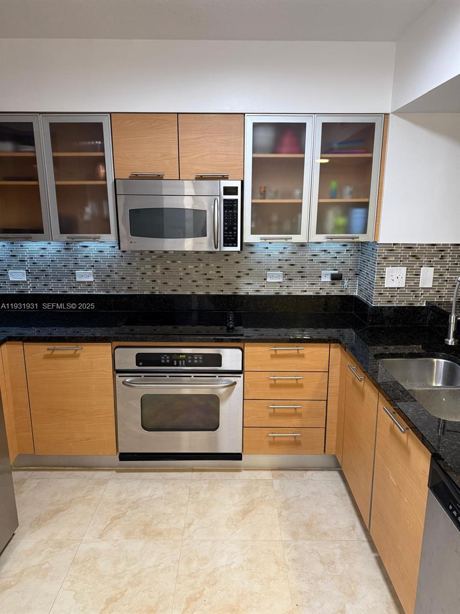 31 Southeast 5th Street, Unit 2907 Miami, FL 33131 - Photo 6 of 38 a kitchen with granite countertop a sink and a stove