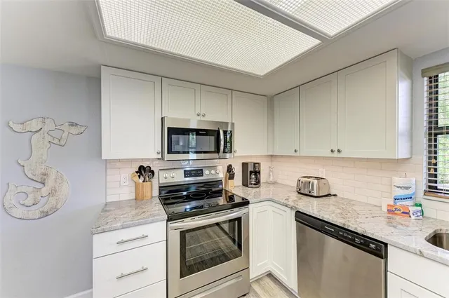 a kitchen with stainless steel appliances granite countertop a sink a stove and cabinets