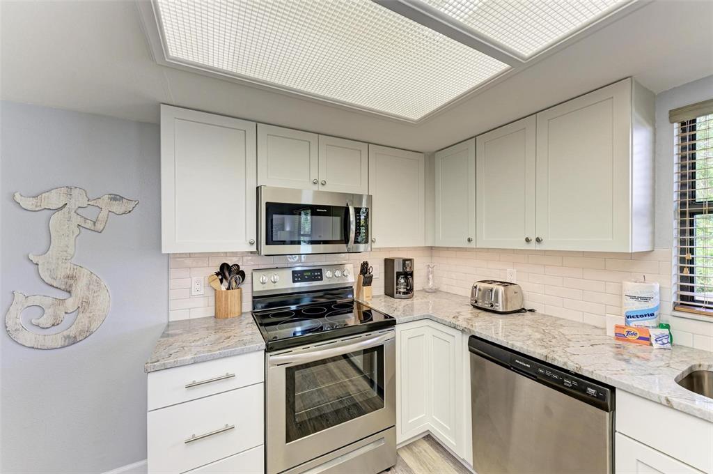 304 74th Street, Unit B Holmes Beach, FL 34217 - Photo 12 of 34 a kitchen with stainless steel appliances granite countertop a sink a stove and cabinets