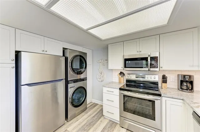 a view of kitchen with stainless steel appliances granite countertop a stove a washer and a refrigerator