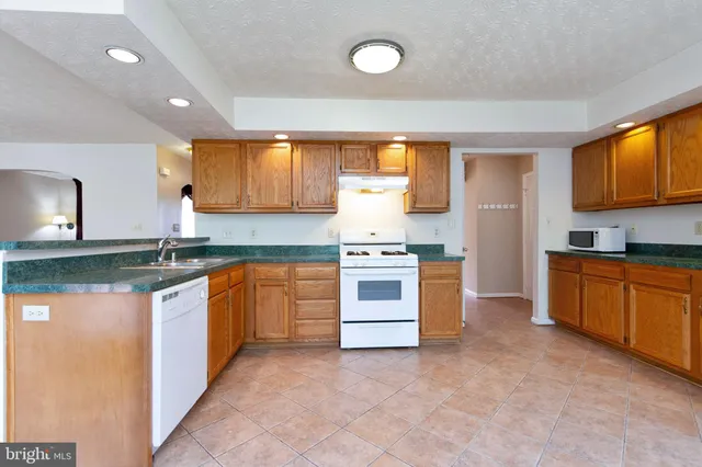a kitchen with granite countertop a stove top oven sink and cabinets